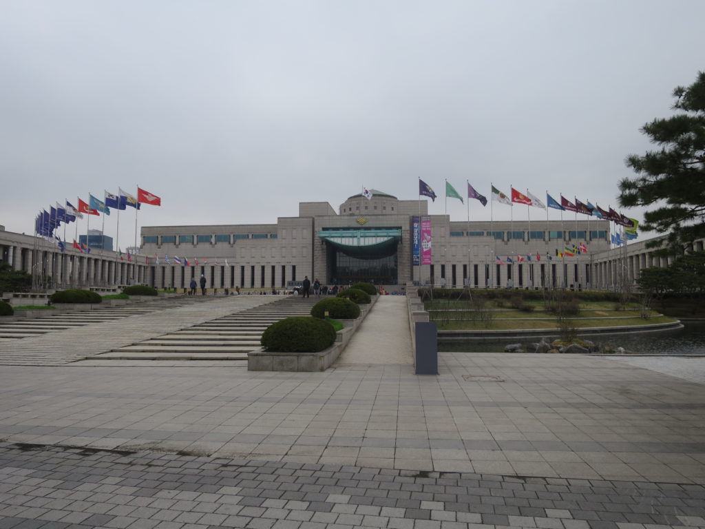 The main museum building, with the flags of participatory countries and units arrayed in a circle around the entrance
